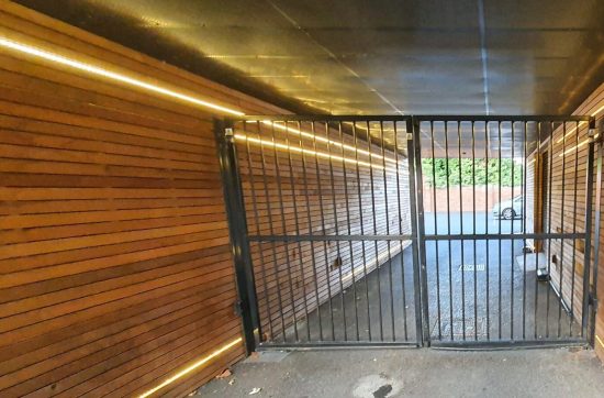 Metal communal access gate in a wood-clad entrance passage