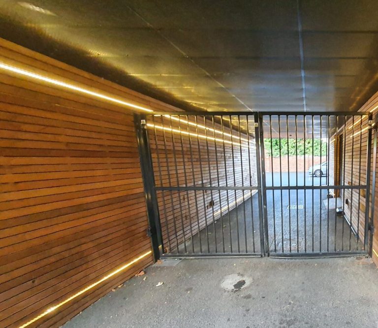 Metal communal access gate in a wood-clad entrance passage